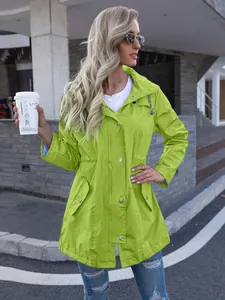 Model wearing a vibrant lime green hooded mid-length windbreaker on a city street