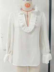 Close-up of white linen blouse with elegant ruffled V-neck and sleeve details