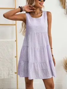 Ärmelloses, gestuftes Minikleid in Lavendelweiß kariert, getragen von einem Model in Innenräumen.