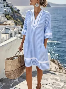 Blue striped V-neck bohemian beach dress with pockets in a scenic seaside resort setting