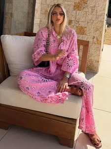 Kaukasisches Model trägt ein rosa Hemd mit Paisley-Print und eine passende weite Hose im Freien