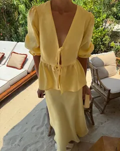 Detailed view of a yellow linen puff sleeve V-neck tie top and high waist skirt set