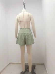 Back view detail of high-waisted sage green cotton linen skirt-shorts on mannequin