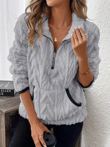 Détail de la texture en peluche et de la demi-fermeture éclair sur ce sweat-shirt gris.