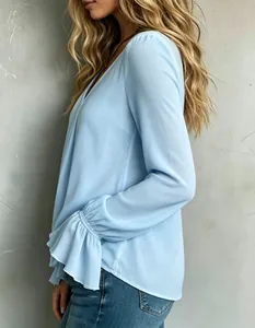 Detail view of elegant light blue blouse showing pleated ruffle cuffs and soft fabric