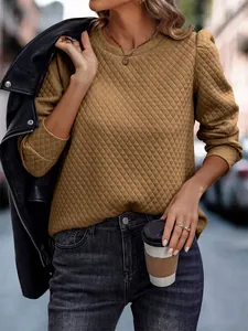 Close-up view of a khaki quilted puff-sleeve sweatshirt styled with a black leather jacket