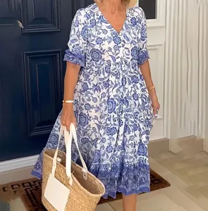 Detailansicht eines blau-weißen Blumen-Midi-Kleides mit Batikmuster und einer Strohtasche.