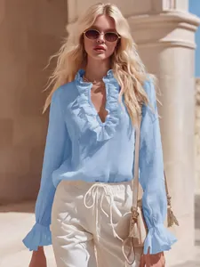 Close-up of a light blue French style linen blouse with elegant ruffle details on V-neck.