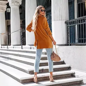 Elegant women's golden velvet blazer with long sleeves and back slit outdoors