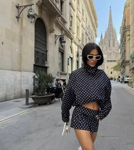 Detailansicht eines Models in einer schwarz-weißen Punktejacke und Shorts auf der Straße