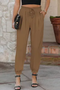 Detail of high waist drawstring jogger pants with elastic cuffs and pocket design.