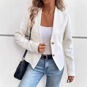 Detailansicht eines weißen, strukturierten Blazers mit langen Ärmeln und goldenen Knöpfen.