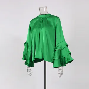 Close-up of elegant green satin blouse with tiered ruffle sleeves on a clear mannequin.