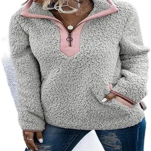 Pull en polaire sherpa gris chaud doté d'un col zippé rose et de poches latérales.