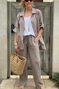 Elegante reife Frau im lässigen beigen Leinenhemd und Hosenset mit großer Strohtasche