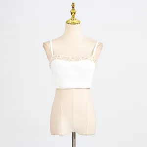 Detail of white sleeveless crop top featuring elegant beaded trim on neckline