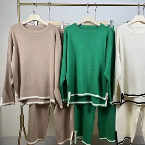 Detail of knitwear sets in multiple colors featuring contrast stripes and side slits.