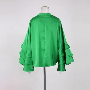 Detailed back view of a green satin blouse with tiered ruffle sleeves on a mannequin.
