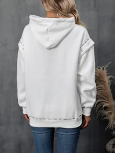 Back view of white oversized hooded sweatshirt with shoulder metal eyelet details.