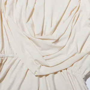 Vue détaillée montrant l'élégant col drapé et la texture plissée sur le tissu crème