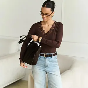 Detail view of brown long sleeve top with delicate lace V-neckline worn by a model