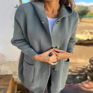 Dettaglio di un cardigan in maglia grigia da donna con cappuccio, bottoni e tasche laterali.