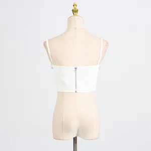 Back view of white cropped camisole top with thin straps and silver zipper