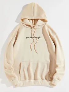 Detail of 'you are enough' text print on a beige fleece hoodie with kangaroo pocket