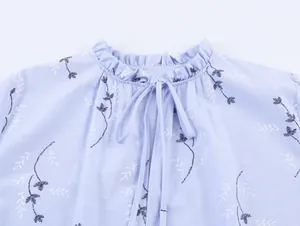 Detailweergave van de ruisjeskraag en bloemenborduurwerk op een lichtblauwe blouse