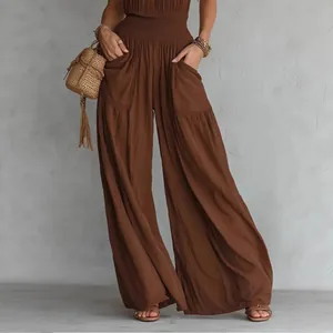 Detail view of brown bohemian smocked waist wide leg jumpsuit with pockets and flowy legs.