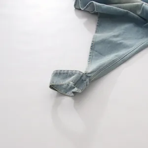 Détail en gros plan montrant la coupe irrégulière et le denim d'un jean vintage bleu clair
