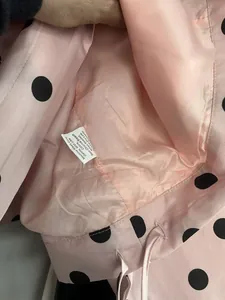Close-up detail view showing the interior lining and care label of a pink polka dot jacket