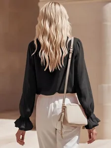 Back view of elegant black French linen blouse with ruffled cuffs and wavy blonde hair