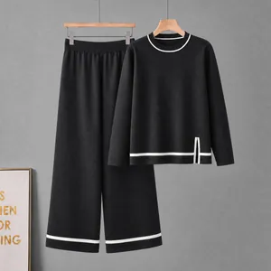 Detailed view of black knit two-piece set with contrast white stripes and side slit.