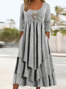 Detailed view of grey long-sleeve tiered maxi dress with heart buckle accent on bust