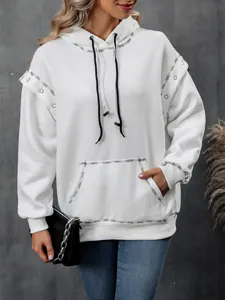 Close-up detail of white oversized hoodie featuring silver eyelet shoulder accents