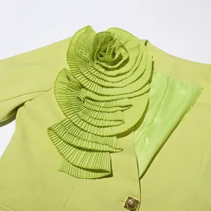 Detailed macro view of pleated 3D flower appliqué on a lime green tailored blazer jacket