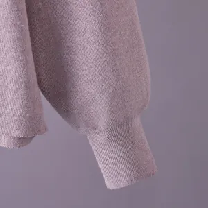Close-up detail of the ribbed cuff on a soft mauve knit sweater, showing textile quality