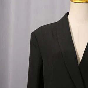 Détail d'un blazer noir montrant le revers pointu et la texture de tissu de qualité