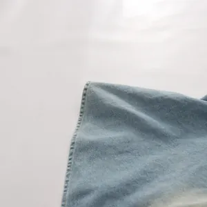 Gros plan sur un denim vintage délavé bleu clair montrant un bord cousu de qualité