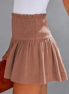 Detail view of high-waisted smocked cotton linen skirt shorts in brown breathable fabric