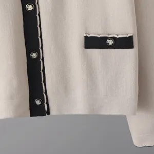 Détail de gilet en maille beige avec boutons argentés à tête de lion en relief