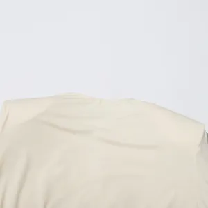 Gros plan d'un haut beige minimaliste pour femme avec épaulettes et encolure chic