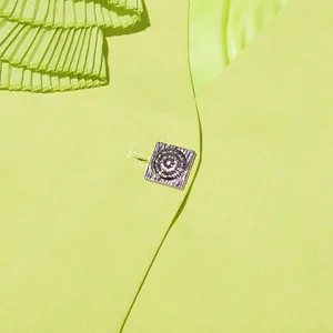Detailed close-up of a lime green blazer featuring a decorative silver metal button.