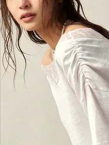 Macro view showing the elegant lace neckline detail of a white off-shoulder Bohemian top