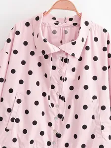 Macro detail view of a pink jacket with black polka dots, buttons and drawstring.