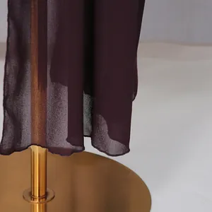 Gros plan sur le tissu en mousseline bordeaux avec ourlet soigné pour chemise femme.