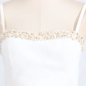 Detailed close-up showing the intricate beaded and sequined neckline on a white camisole top.