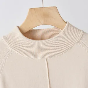 Detailed view of the ribbed round neckline and fine knit texture of a beige sweater
