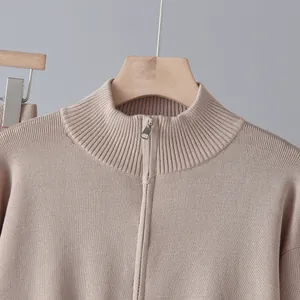 Detail des silbernen Reißverschlusses und des gerippten Kragens eines beigen Strickpullovers